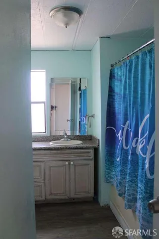 a bathroom with a granite countertop sink a mirror and a shower