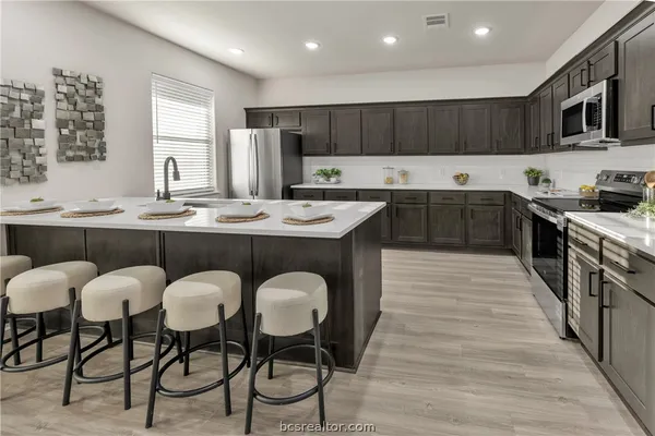 a kitchen with stainless steel appliances granite countertop a table chairs sink refrigerator and cabinets