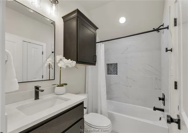 a bathroom with a granite countertop sink toilet a mirror and shower