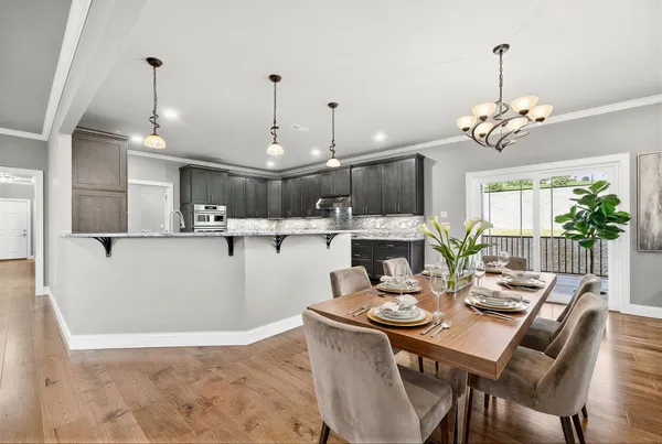 a view of a dining room and livingroom with furniture wooden floor a chandelier