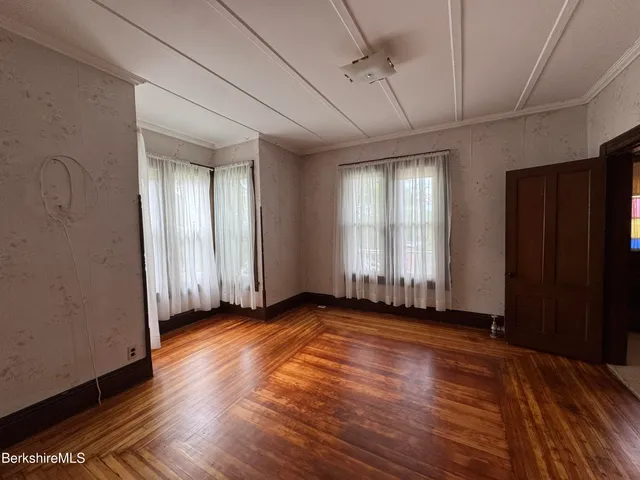a view of an empty room with wooden floor and a window