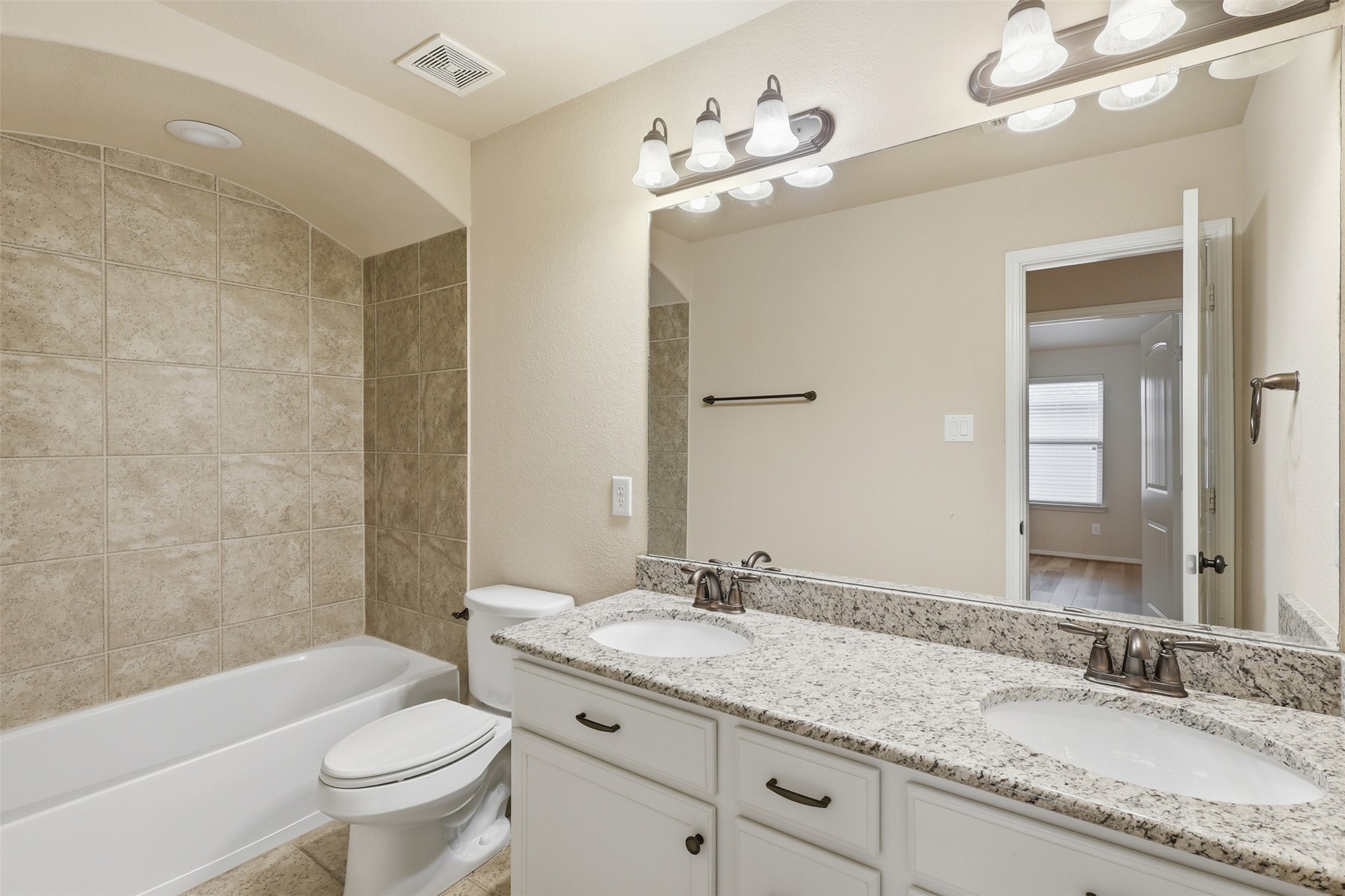 22943 Dale River Road Tomball, TX 77375 - Photo 22 of 29 a bathroom with a granite countertop sink a toilet a mirror a bathtub and shower
