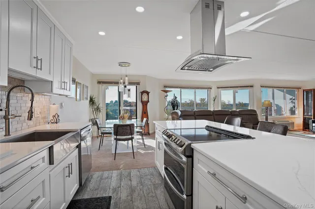 a large white kitchen with stainless steel appliances a sink a stove and a refrigerator