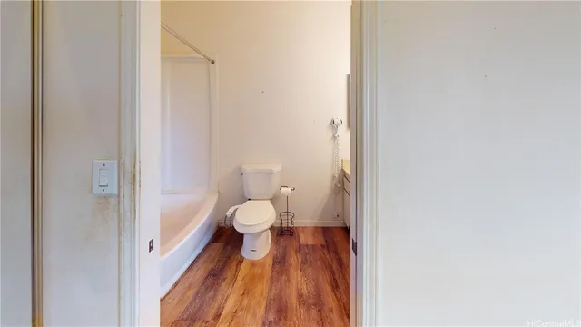 a view of an empty room with wooden floor and windows
