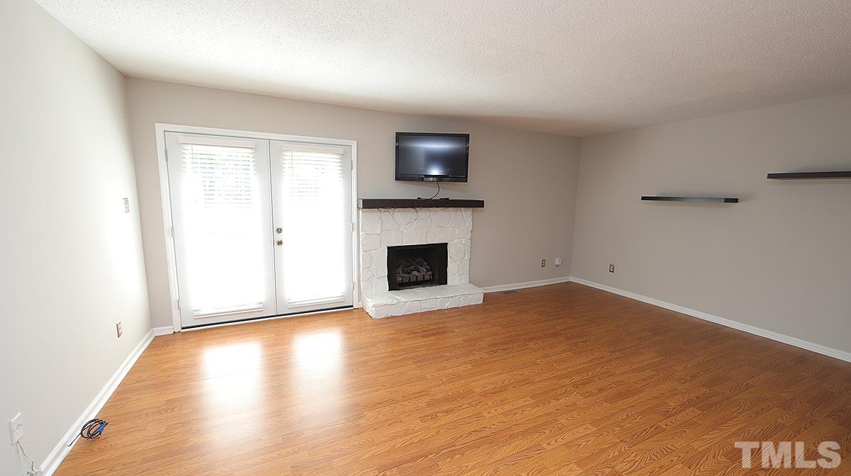 5758 Pool Side Drive Raleigh, NC 27612 - Photo 9 of 24 a view of empty room with wooden floor and fireplace