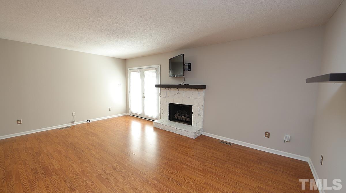 5758 Pool Side Drive Raleigh, NC 27612 - Photo 10 of 24 a view of empty room with wooden floor and fireplace