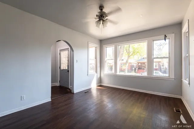 an empty room with wooden floor chandelier and windows