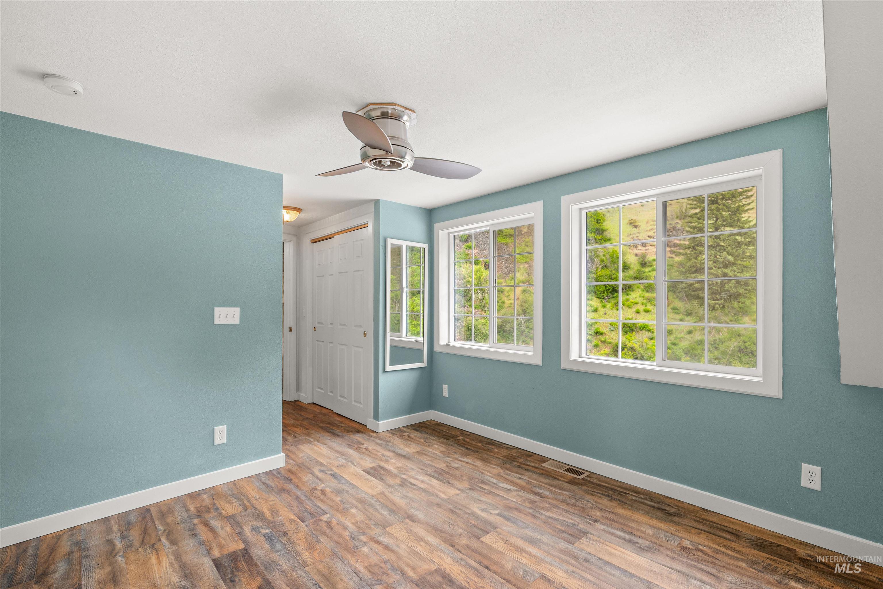 1314 Cedar Ridge Road Kendrick, ID 83537 - Photo 27 of 50 Room featuring wood-finish flooring, two large windows with grid patterns, and a ceiling fan with integrated lighting