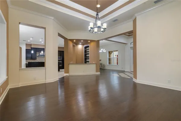 a view of a big room with wooden floor chandelier and windows