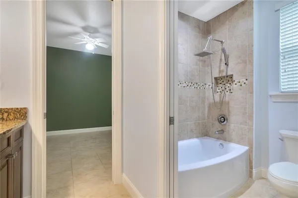 a bathroom with a granite countertop bathtub shower and toilet