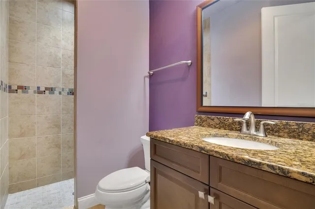 a bathroom with a granite countertop sink a toilet and shower