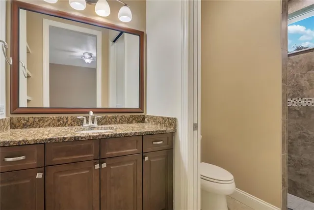a bathroom with a granite countertop sink toilet and mirror