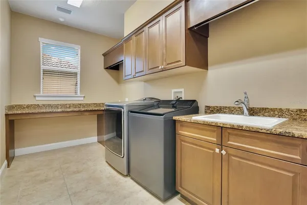 a utility room with granite countertop cabinets washer and dryer