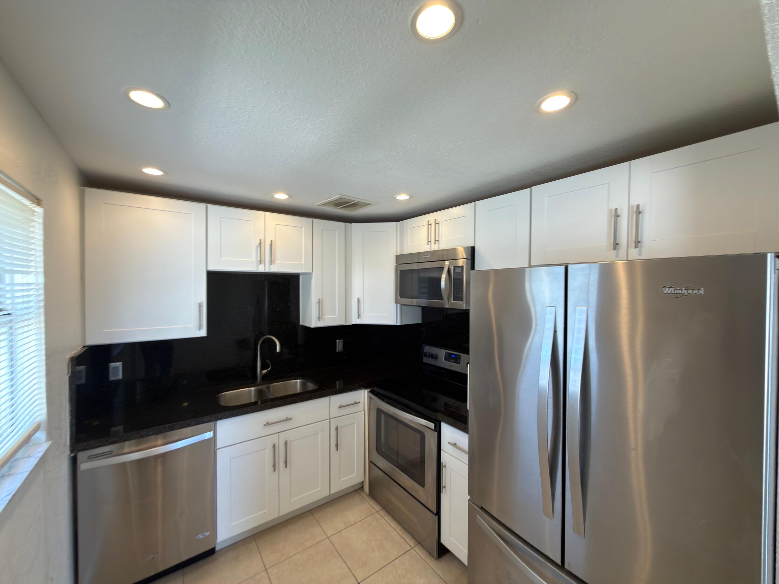 741 Monaco P, Unit 741 Delray Beach, FL 33446 - Photo 11 of 18 a kitchen with a refrigerator and a sink