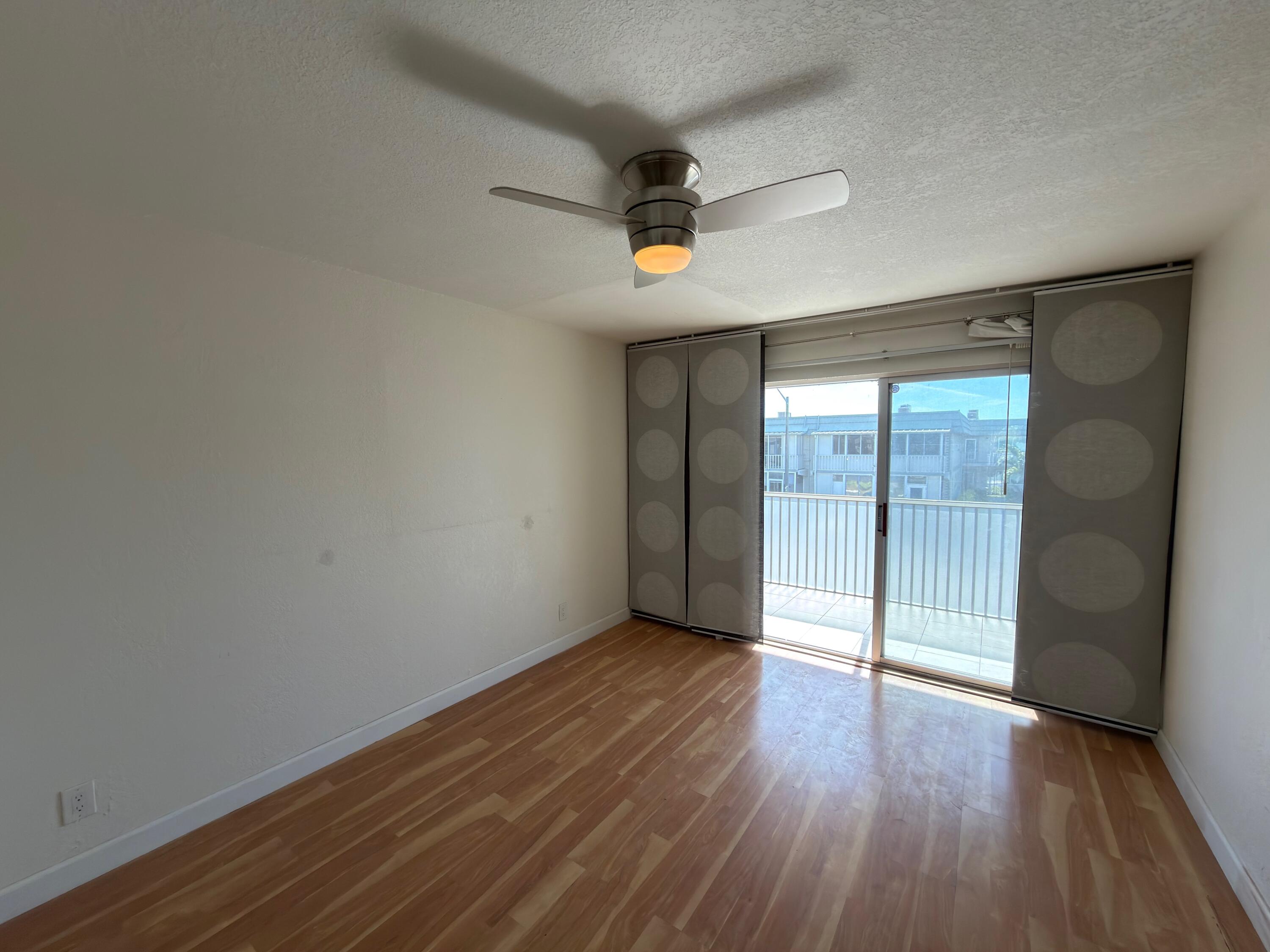 741 Monaco P, Unit 741 Delray Beach, FL 33446 - Photo 13 of 18 an empty room with wooden floor and windows