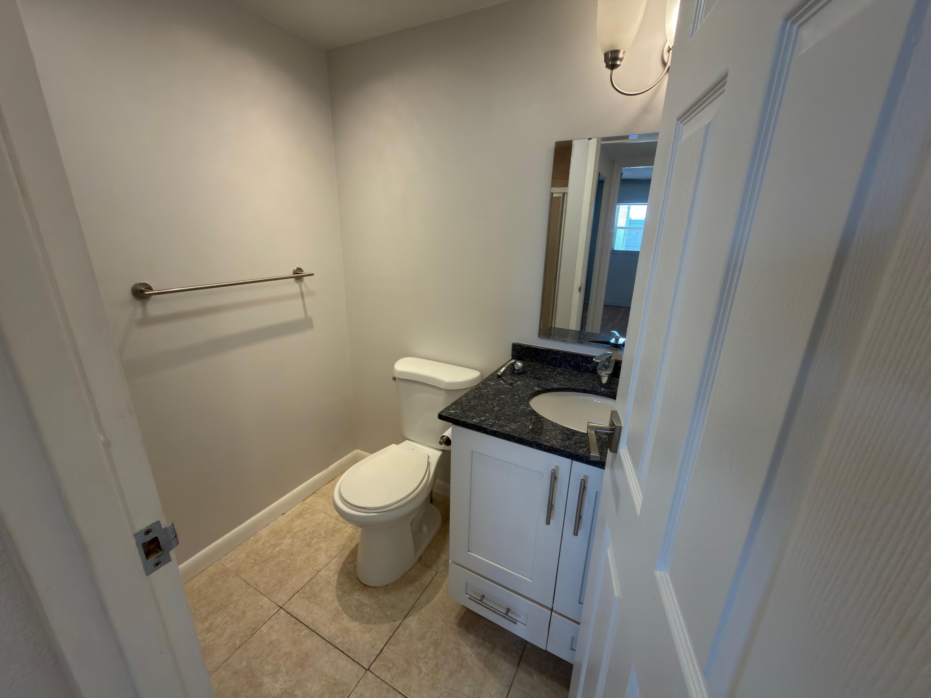 741 Monaco P, Unit 741 Delray Beach, FL 33446 - Photo 16 of 18 a bathroom with a granite countertop sink toilet and mirror