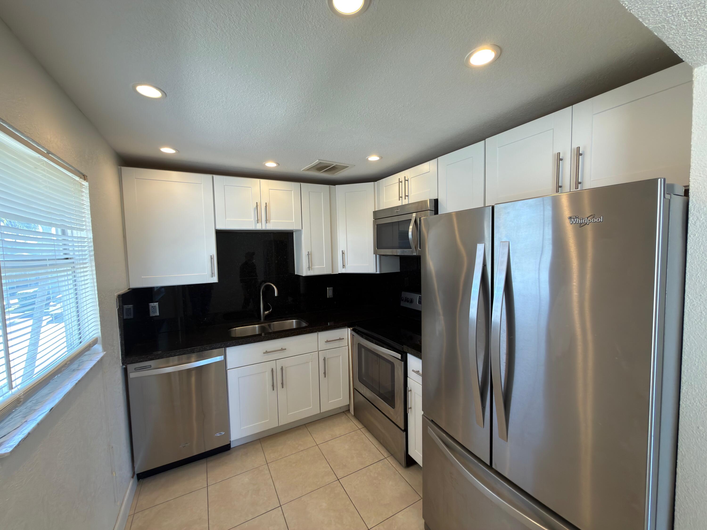 741 Monaco P, Unit 741 Delray Beach, FL 33446 - Photo 8 of 18 a kitchen with stainless steel appliances granite countertop a refrigerator a sink and white cabinets