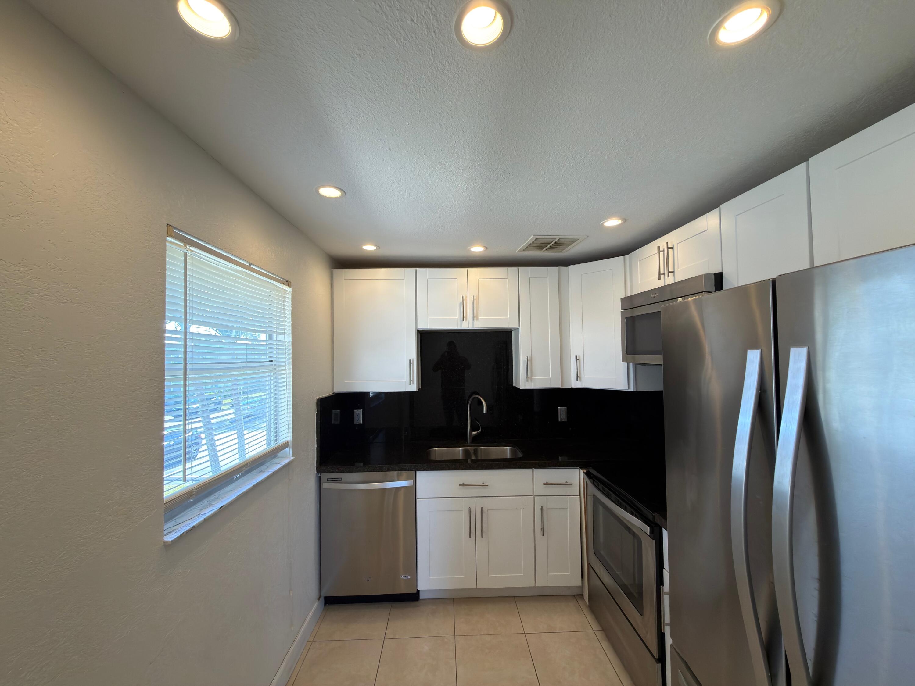 741 Monaco P, Unit 741 Delray Beach, FL 33446 - Photo 9 of 18 a kitchen with a refrigerator and a stove top oven