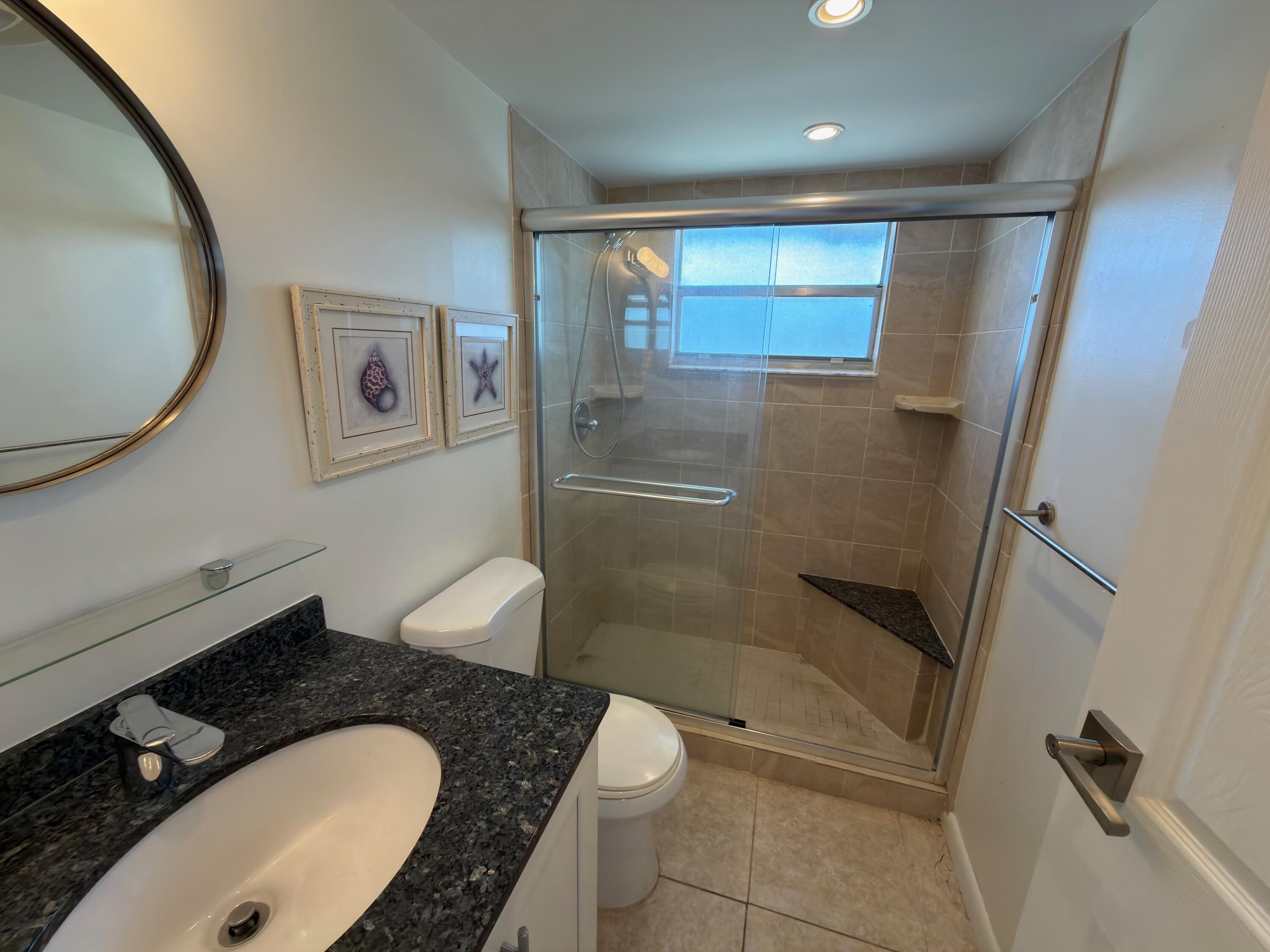 741 Monaco P, Unit 741 Delray Beach, FL 33446 - Photo 10 of 18 a bathroom with a granite countertop sink toilet and shower