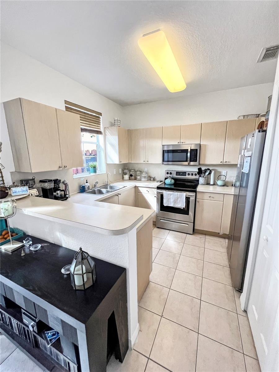 12524 Southwest 126th Avenue Miami, FL 33186 - Photo 11 of 23 a kitchen with a stove a sink and a refrigerator