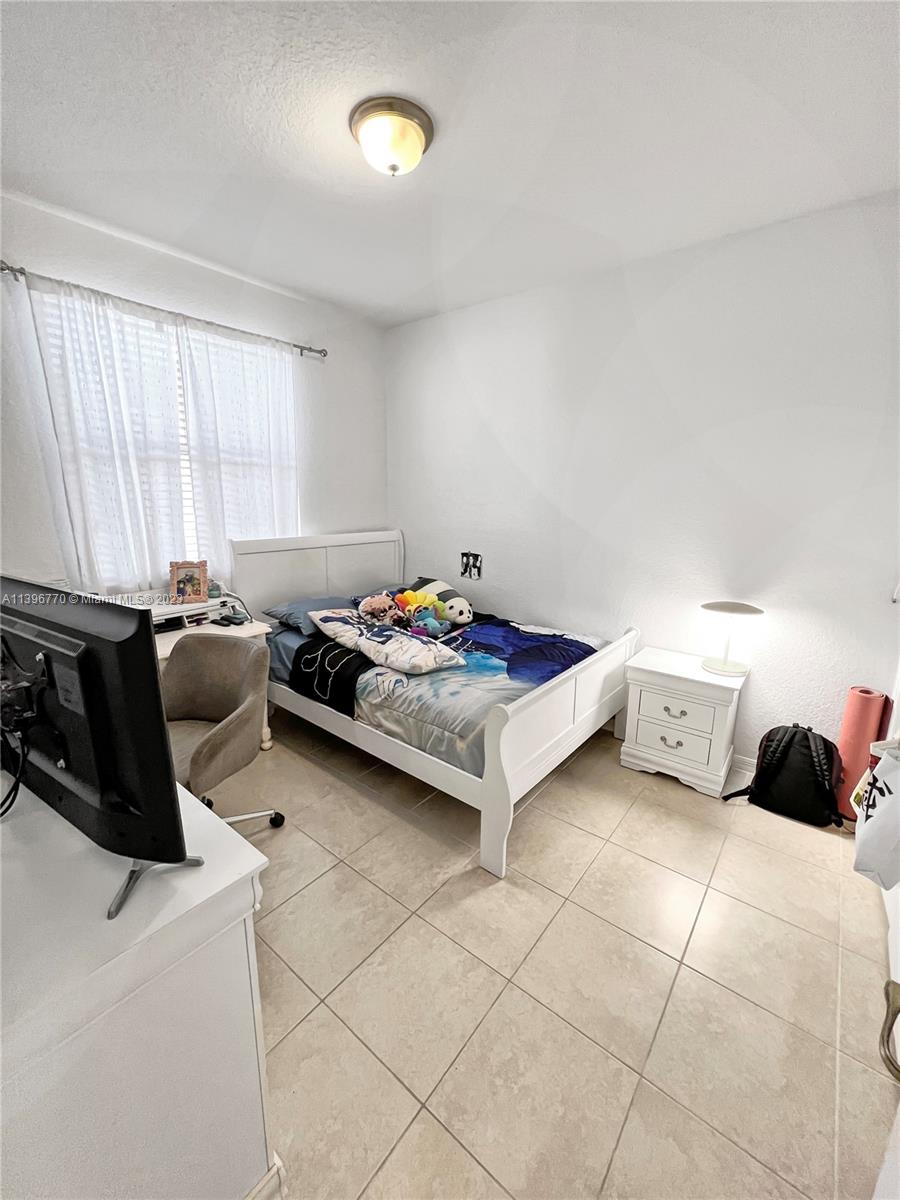 12524 Southwest 126th Avenue Miami, FL 33186 - Photo 19 of 23 a bedroom with a bed a table and chair