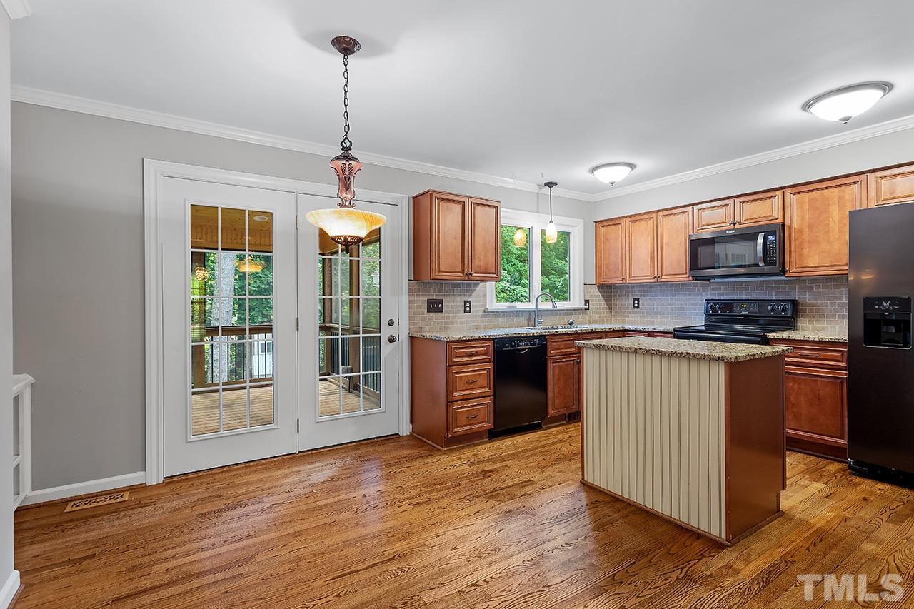 8408 Morgans Way Raleigh, NC 27613 - Photo 11 of 34 a kitchen with stainless steel appliances granite countertop a refrigerator a sink dishwasher a stove and a dining table with wooden floor