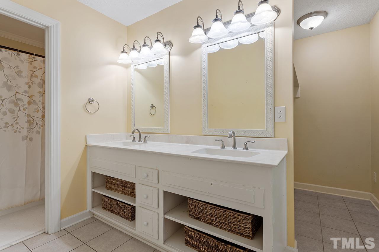 8408 Morgans Way Raleigh, NC 27613 - Photo 19 of 34 a bathroom with a sink a large mirror and a shower