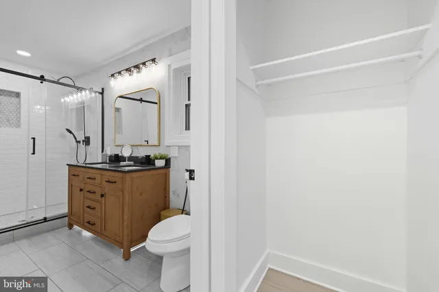 a bathroom with a granite countertop sink toilet mirror and a shower