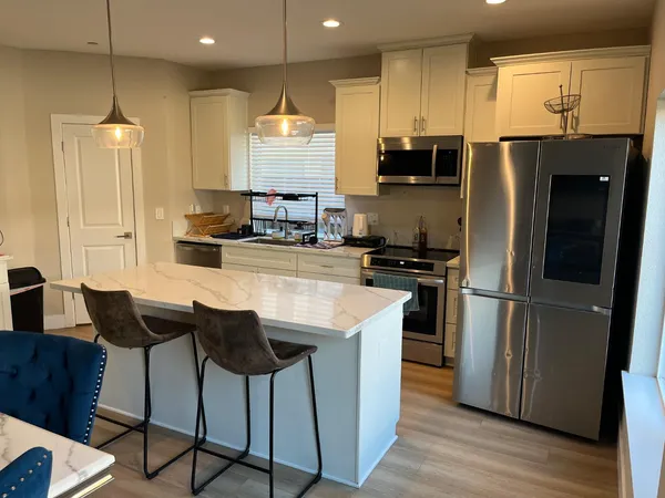 a kitchen with stainless steel appliances granite countertop a refrigerator a stove a sink a dining table and chairs