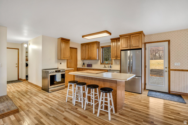 887 Village Way Alpine, UT 84004 - Photo 15 of 28 Kitchen featuring light countertops, stainless steel appliances, wallpapered walls, a kitchen breakfast bar, and a center island