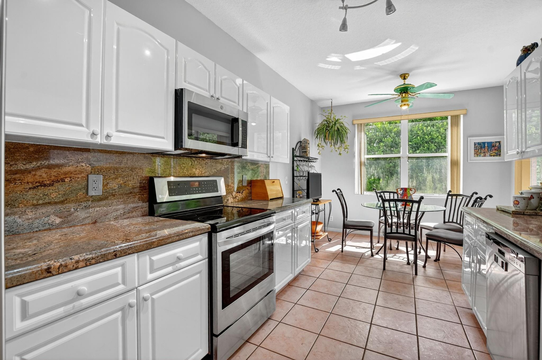 12614 Tiboli Chase Court, Unit 1 Boca Raton, FL 33496 - Photo 15 of 62 a kitchen with stainless steel appliances granite countertop a stove top oven a sink dishwasher a dining table and chairs with wooden floor