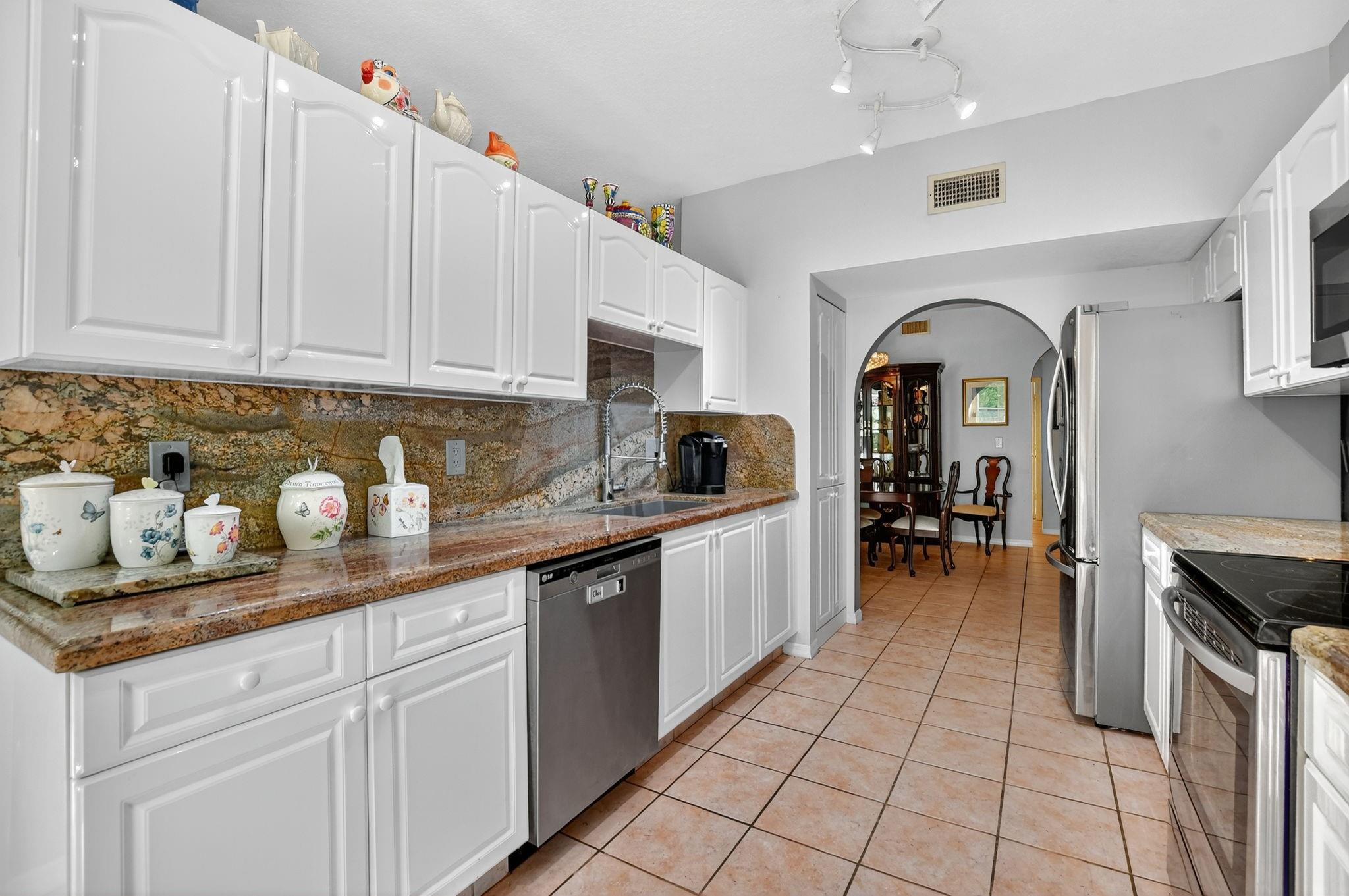 12614 Tiboli Chase Court, Unit 1 Boca Raton, FL 33496 - Photo 16 of 62 a kitchen with granite countertop a sink a stove and cabinets