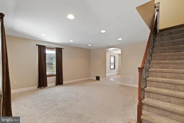 a view of an empty room with wooden floor and stairs