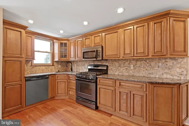 a kitchen with granite countertop wooden cabinets stainless steel appliances and a window