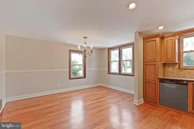 an empty room with wooden floor cabinet and windows