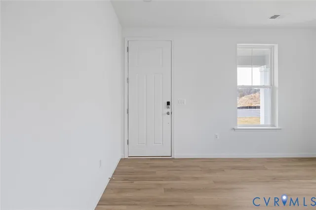 a view of an empty room with window and closet area