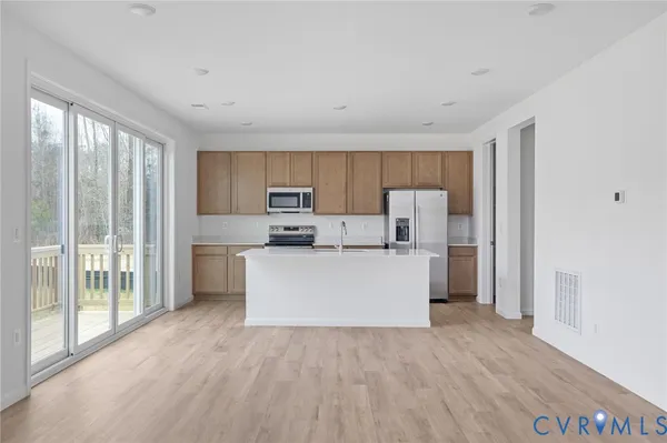 a view of kitchen with stainless steel appliances wooden floor and window