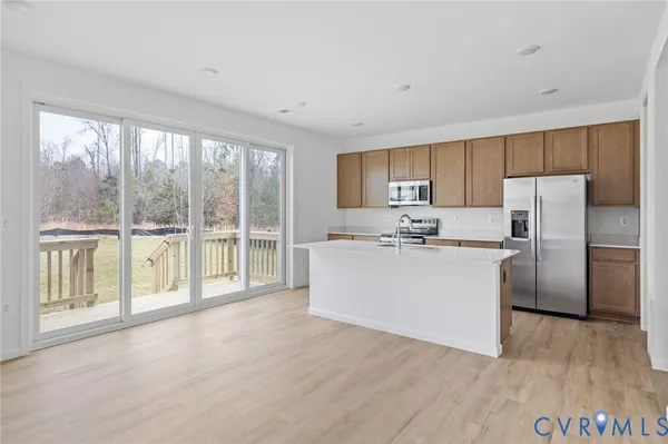 a room with kitchen island a large window cabinets a sink and a refrigerator