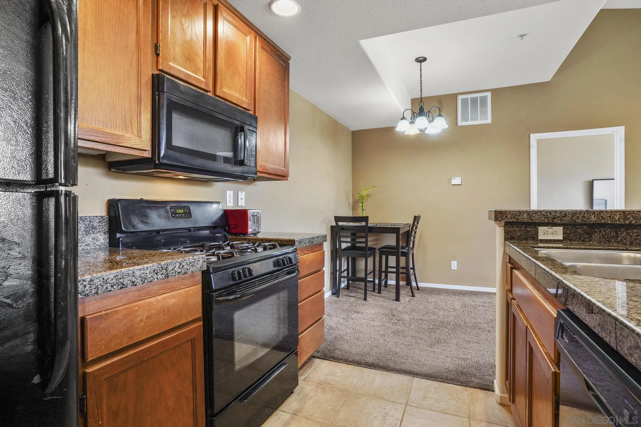 1853 Rue Bienville Place, Unit 833 Chula Vista, CA 91913 - Photo 11 of 23 a kitchen with stainless steel appliances granite countertop a stove top oven a sink and a microwave