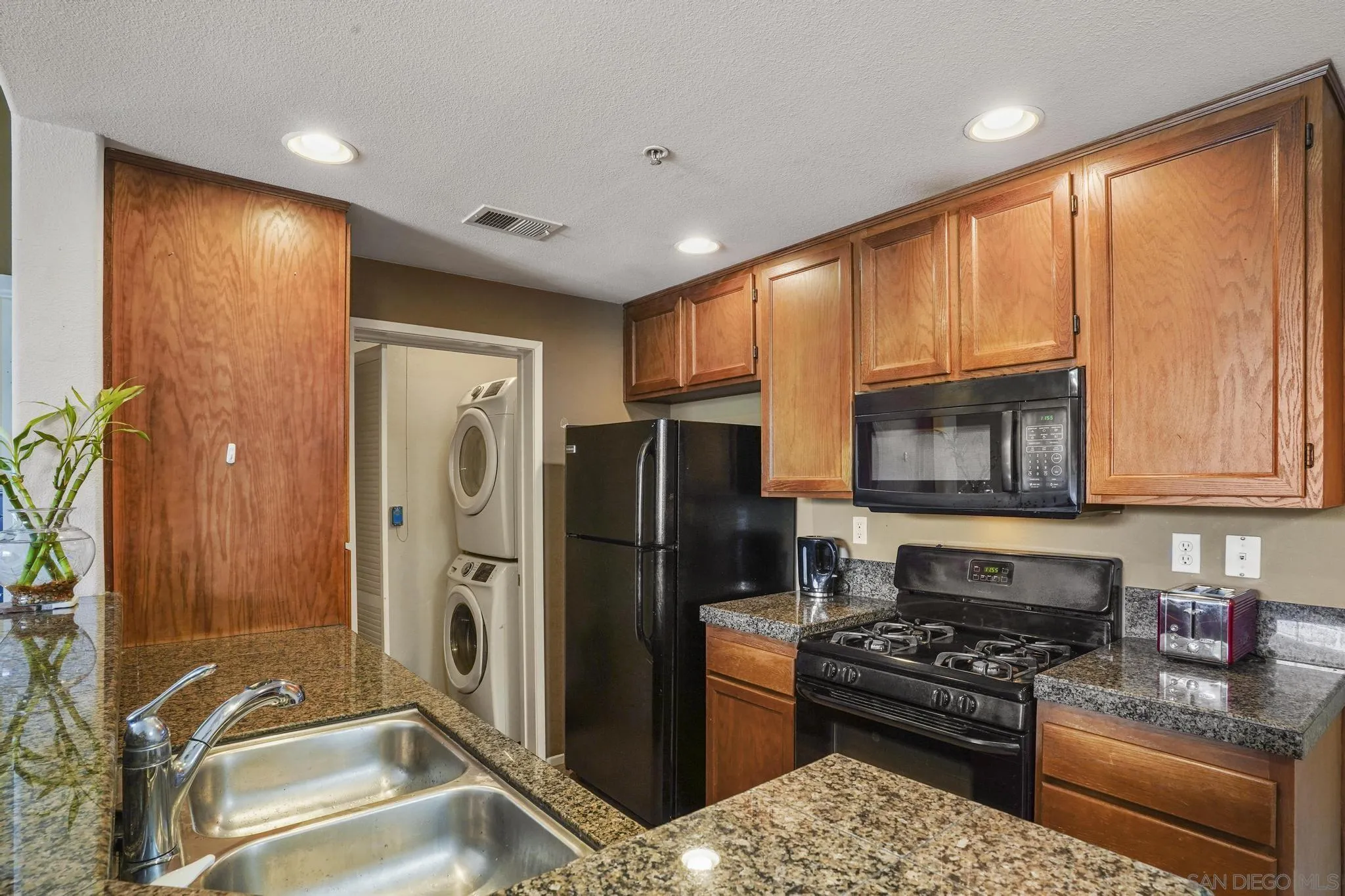 1853 Rue Bienville Place, Unit 833 Chula Vista, CA 91913 - Photo 8 of 23 a kitchen with stainless steel appliances granite countertop a refrigerator stove and sink