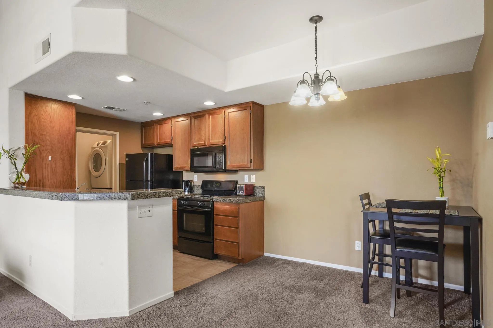 1853 Rue Bienville Place, Unit 833 Chula Vista, CA 91913 - Photo 9 of 23 a kitchen with stainless steel appliances granite countertop a stove top oven a sink dishwasher a dining table and chairs with wooden floor