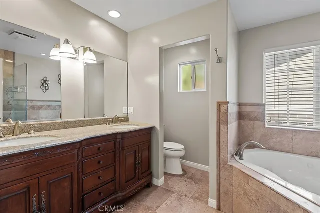 a bathroom with a double vanity sink a toilet and a bathtub