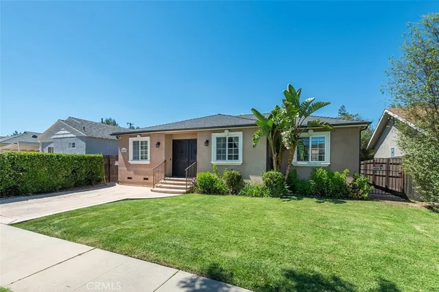 a front view of a house with a yard and potted plants