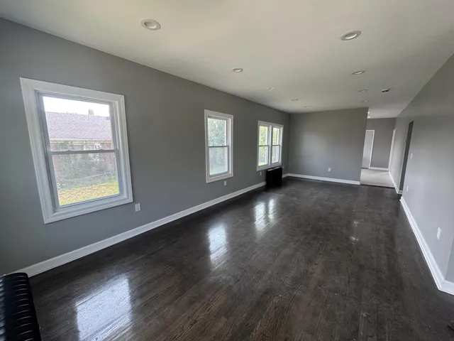 a view of an empty room with wooden floor and windows