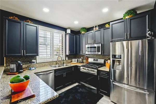 a kitchen with granite countertop stainless steel appliances a sink stove and refrigerator