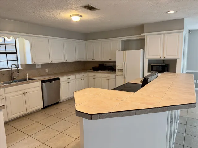 a kitchen with a sink a stove a refrigerator and white cabinets