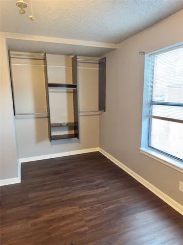 a view of empty room with wooden floor and window
