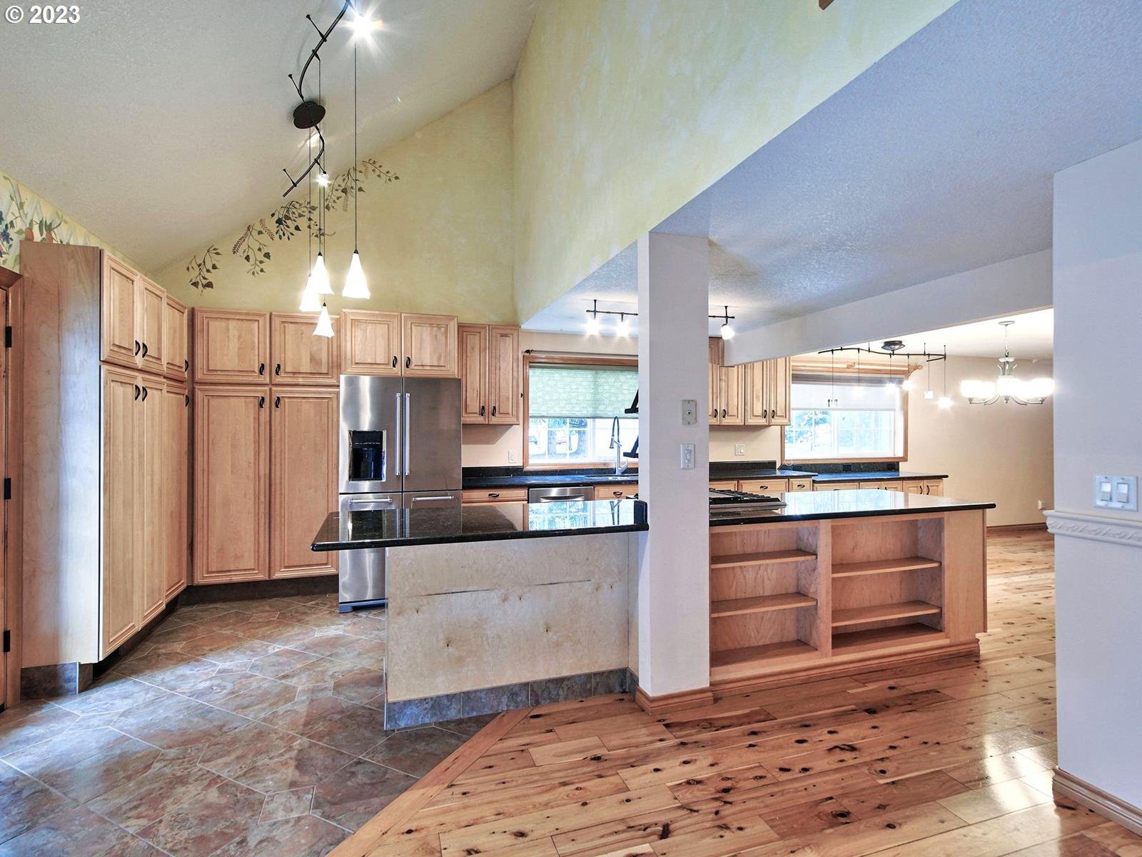 34385 Northeast Sunset Loop Scappoose, OR 97056 - Photo 13 of 42 a large kitchen with stainless steel appliances kitchen island granite countertop a refrigerator oven a sink dishwasher and white cabinets with wooden floor