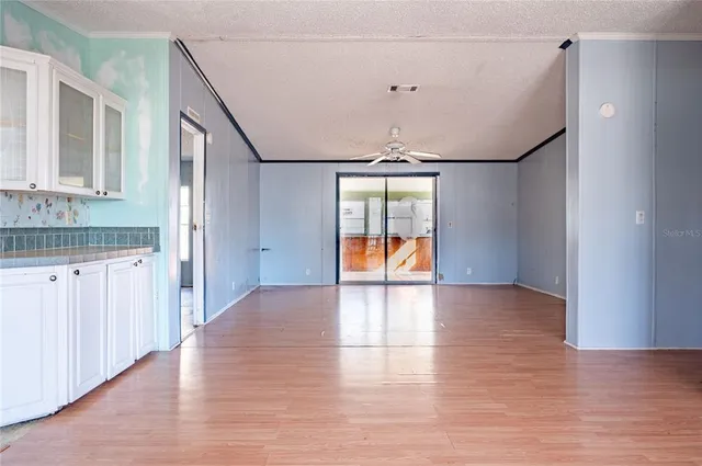 a view of empty room with wooden floor and fan
