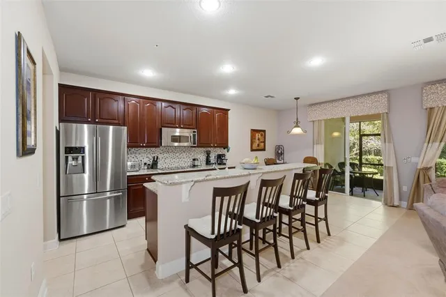 a open kitchen with stainless steel appliances granite countertop a stove top oven a sink a dining table and chairs with wooden floor